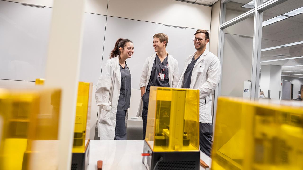 Three coworkers talk in room of advanced 3D printers